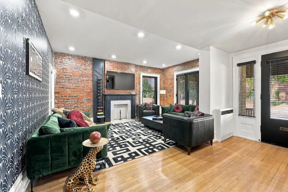 The living room: green velvet sofas, exposed brick and patterned wallpaper