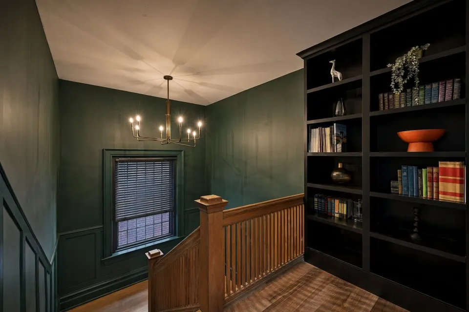 The stair hall: green panelling, brass chandelier and bookshelves